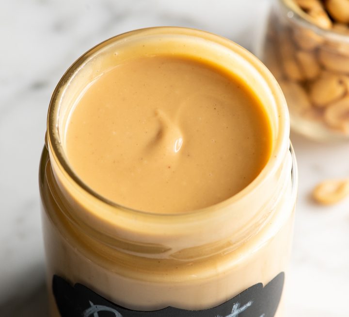 overhead view of a glass jar of homemade peanut butter with the lid off