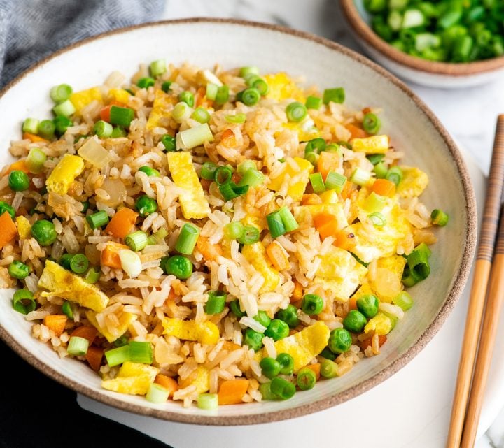 This easy vegetable fried rice recipe is better than takeout! It only takes 20 minutes to make the best fried rice recipe that's flavorful, healthy and loaded with eggs and veggies! front view of a bowl of homemade fried rice