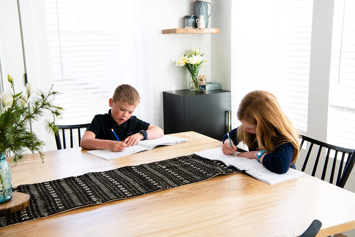 two children practicing handwriting at a table