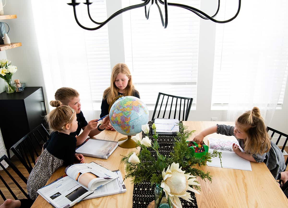 four kids doing homeschool at a table