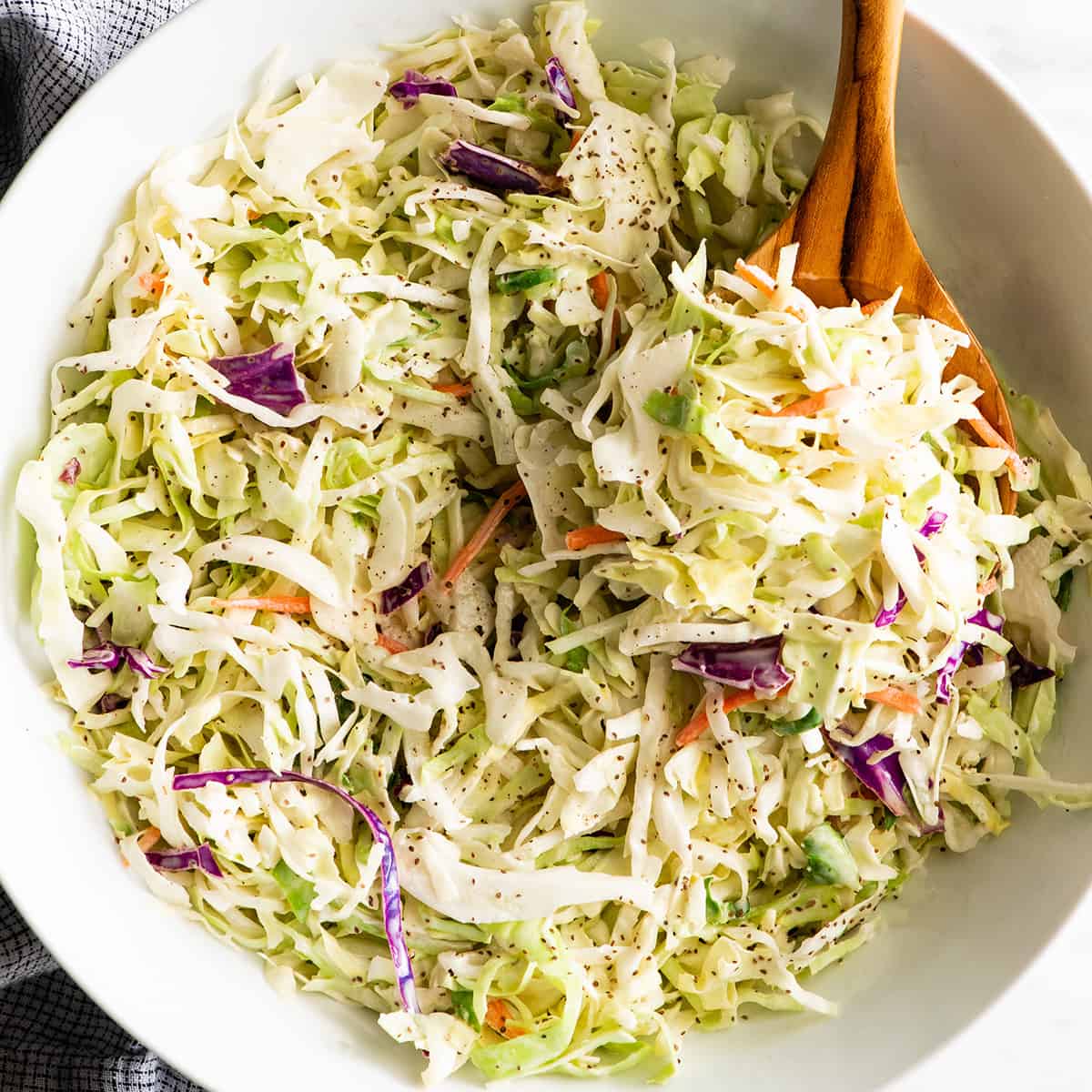 coleslaw in a bowl with a wooden spoon