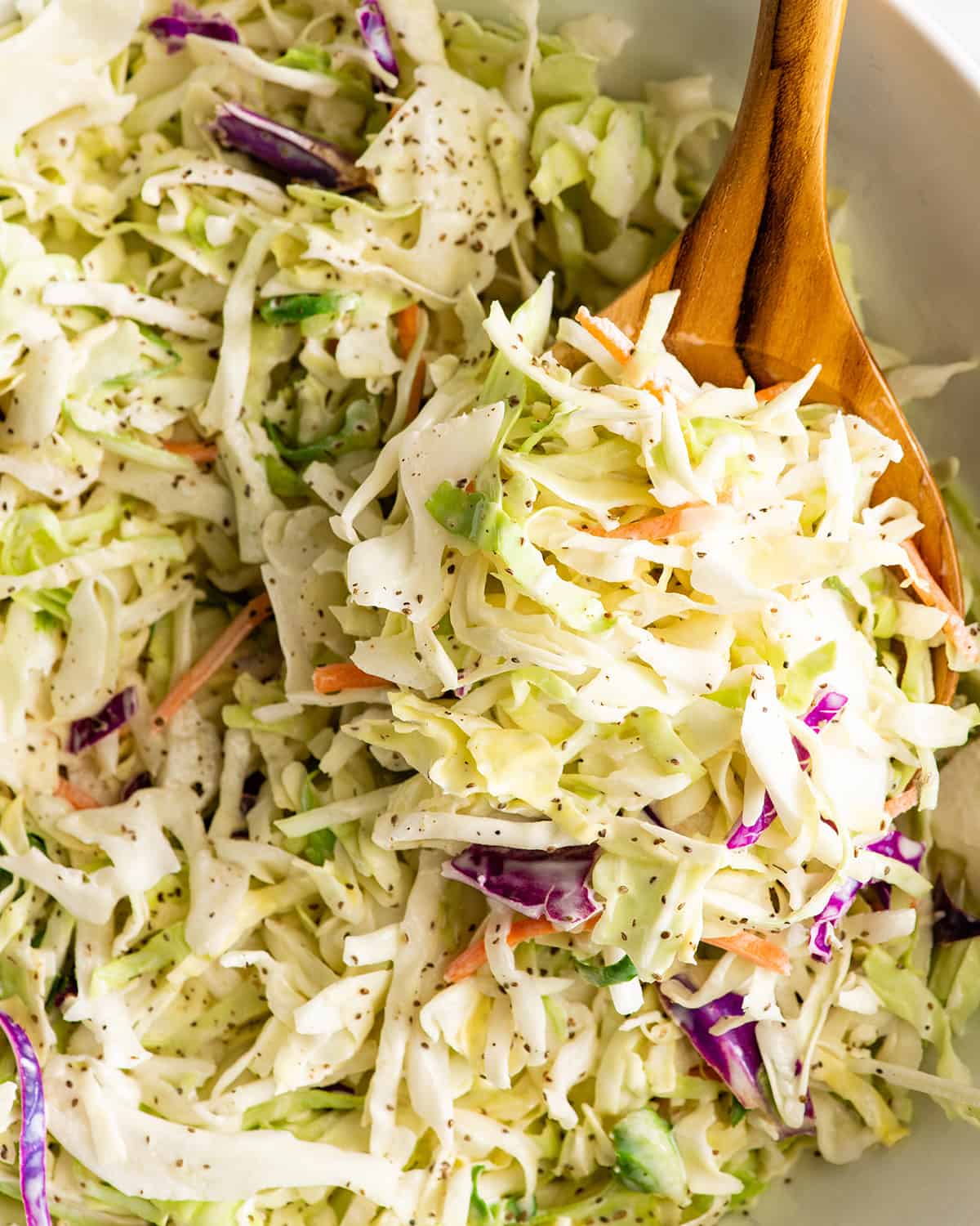 homemade coleslaw recipe in a bowl with a wooden spoon