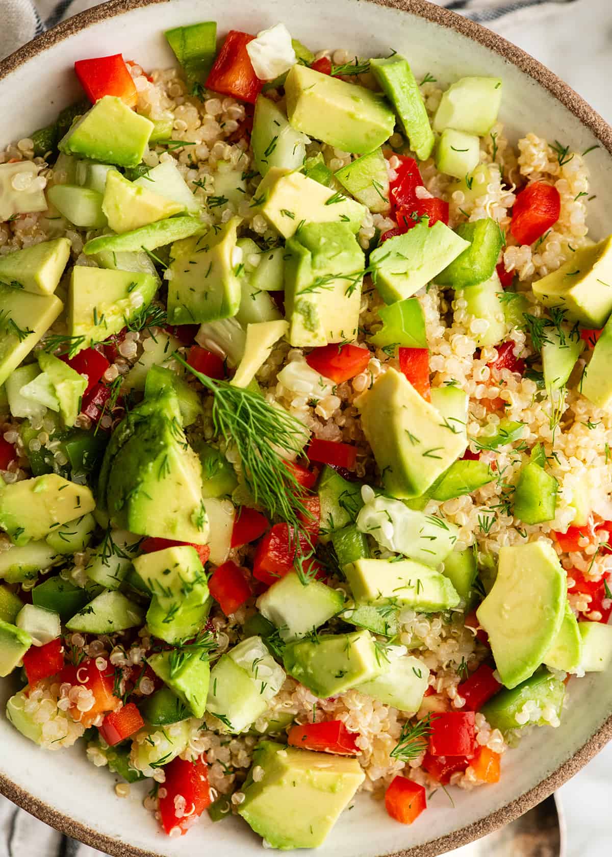 overhead photo of a bowl of quinoa salad with avocado and fresh dill