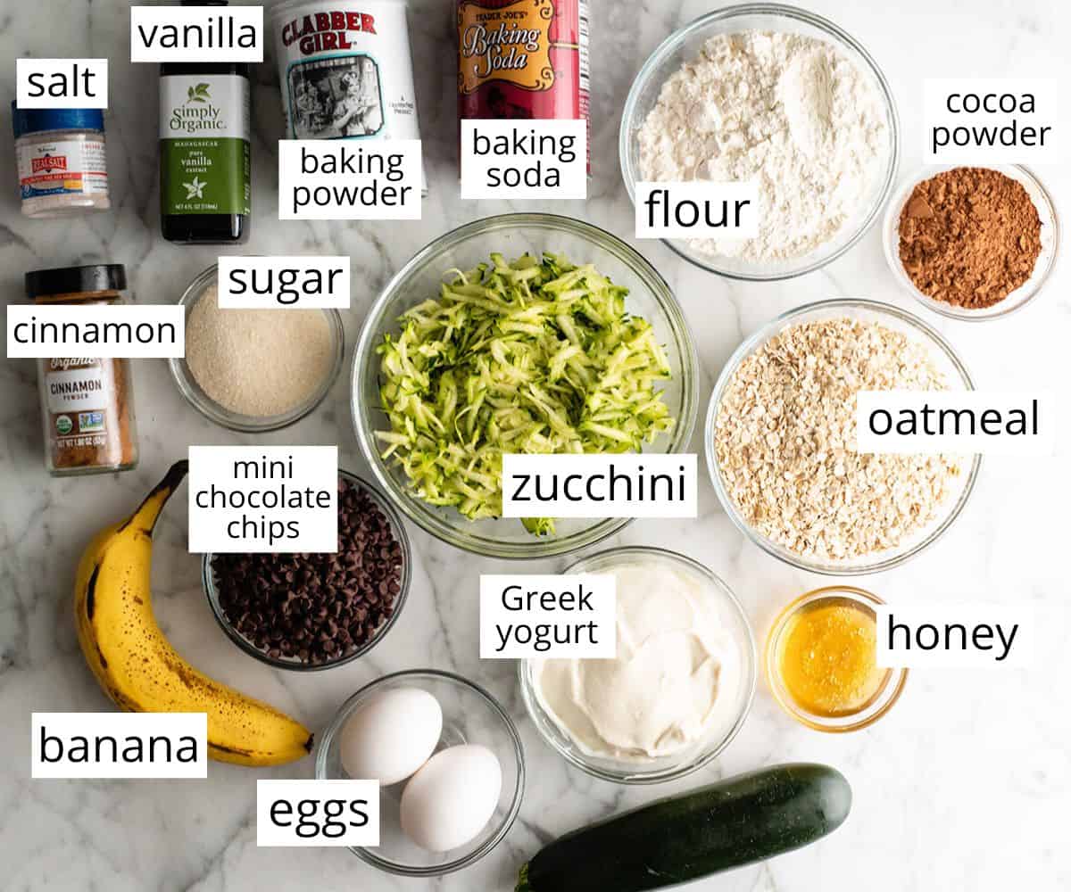overhead photo of the labeled ingredients in this Healthy Chocolate Zucchini Muffins recipe