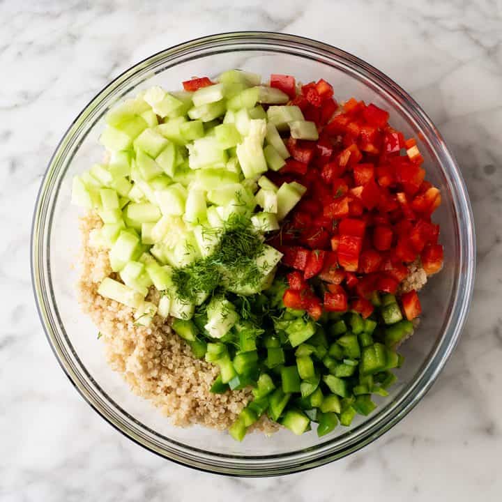 overhead photo showing how to make quinoa salad - adding the vegetables