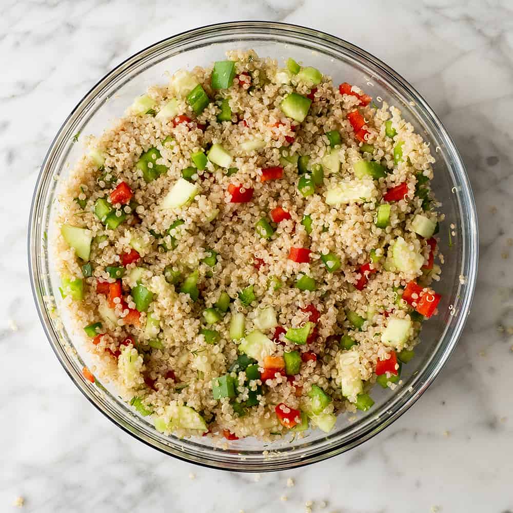 making quinoa salad in a glass bowl 