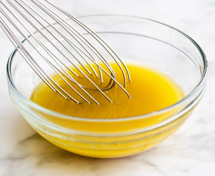 front view of quinoa salad dressing made in a glass bowl with a wire whisk in it
