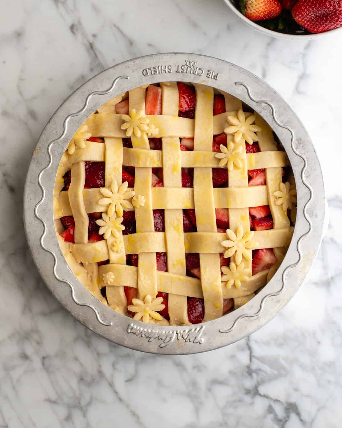 assembled strawberry pie with a pie crust shield before baking