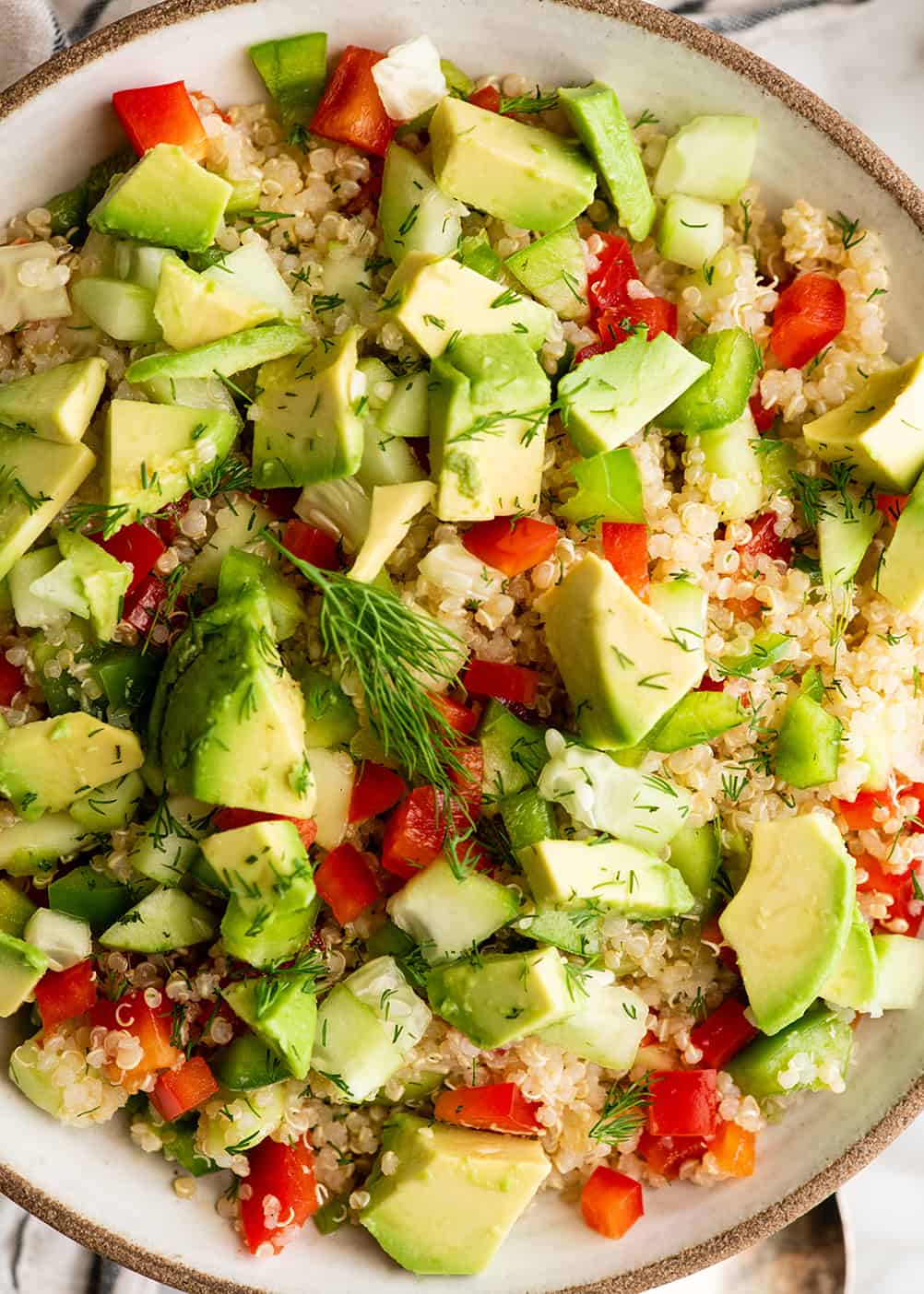up close overhead view of a bowl of quinoa salad garnished with fresh dill