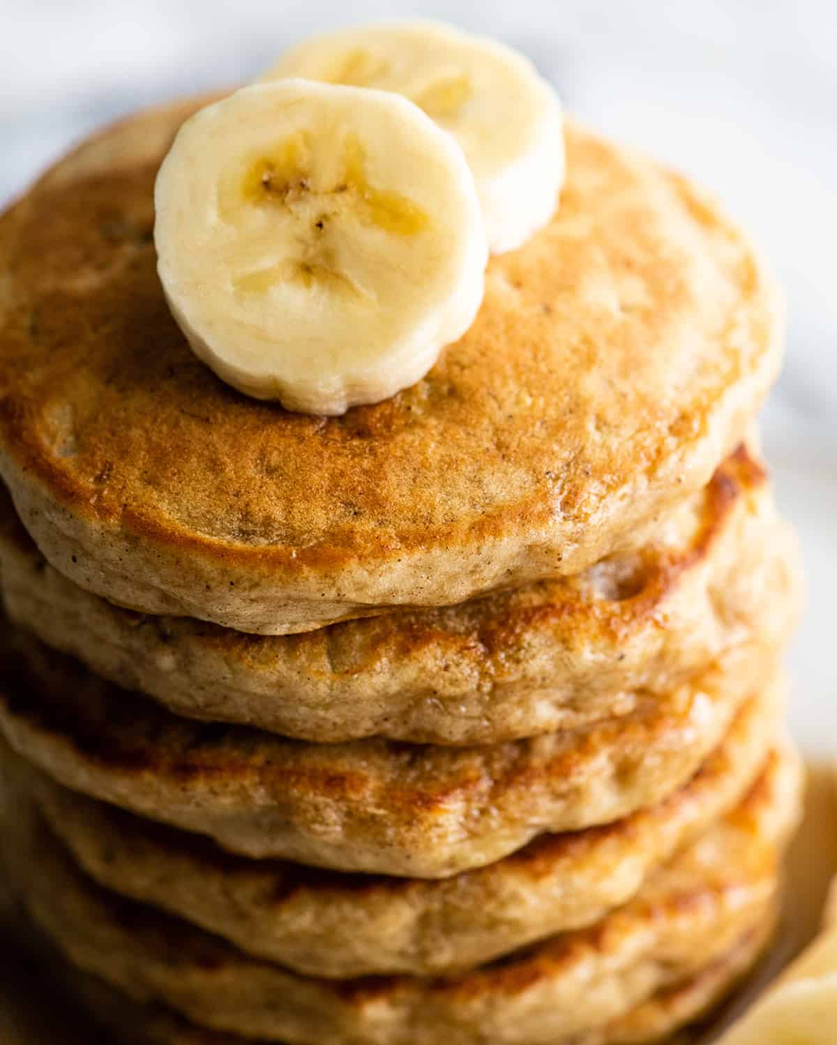 overhead view of a stack of 6 banana pancakes with sliced bananas 