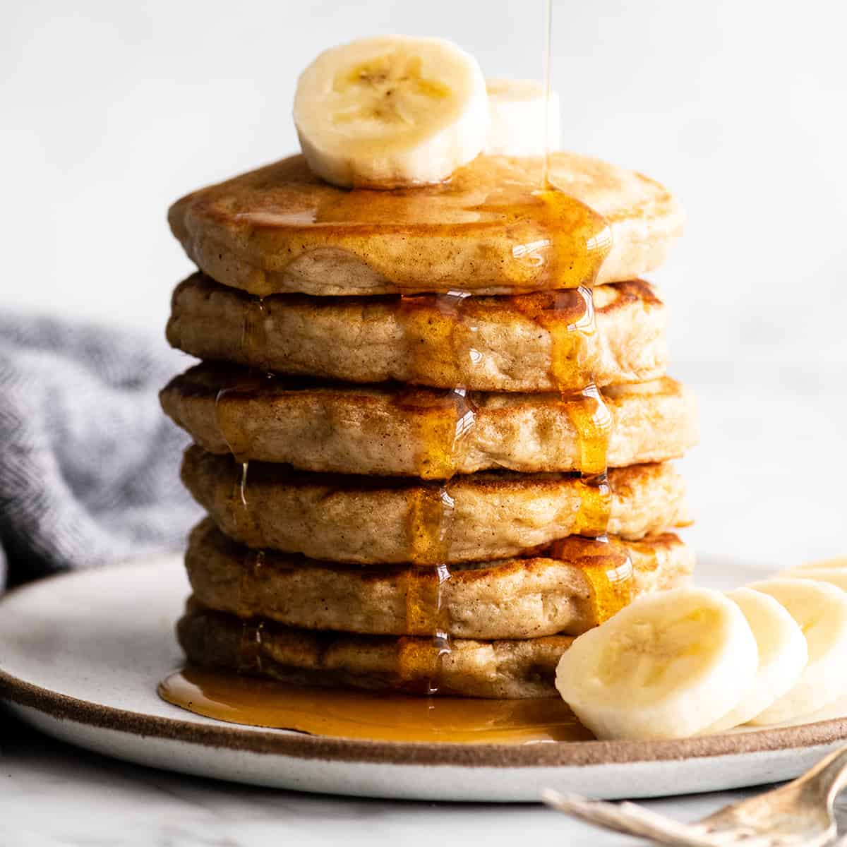 front view of a stack of 6 banana pancakes with syrup 