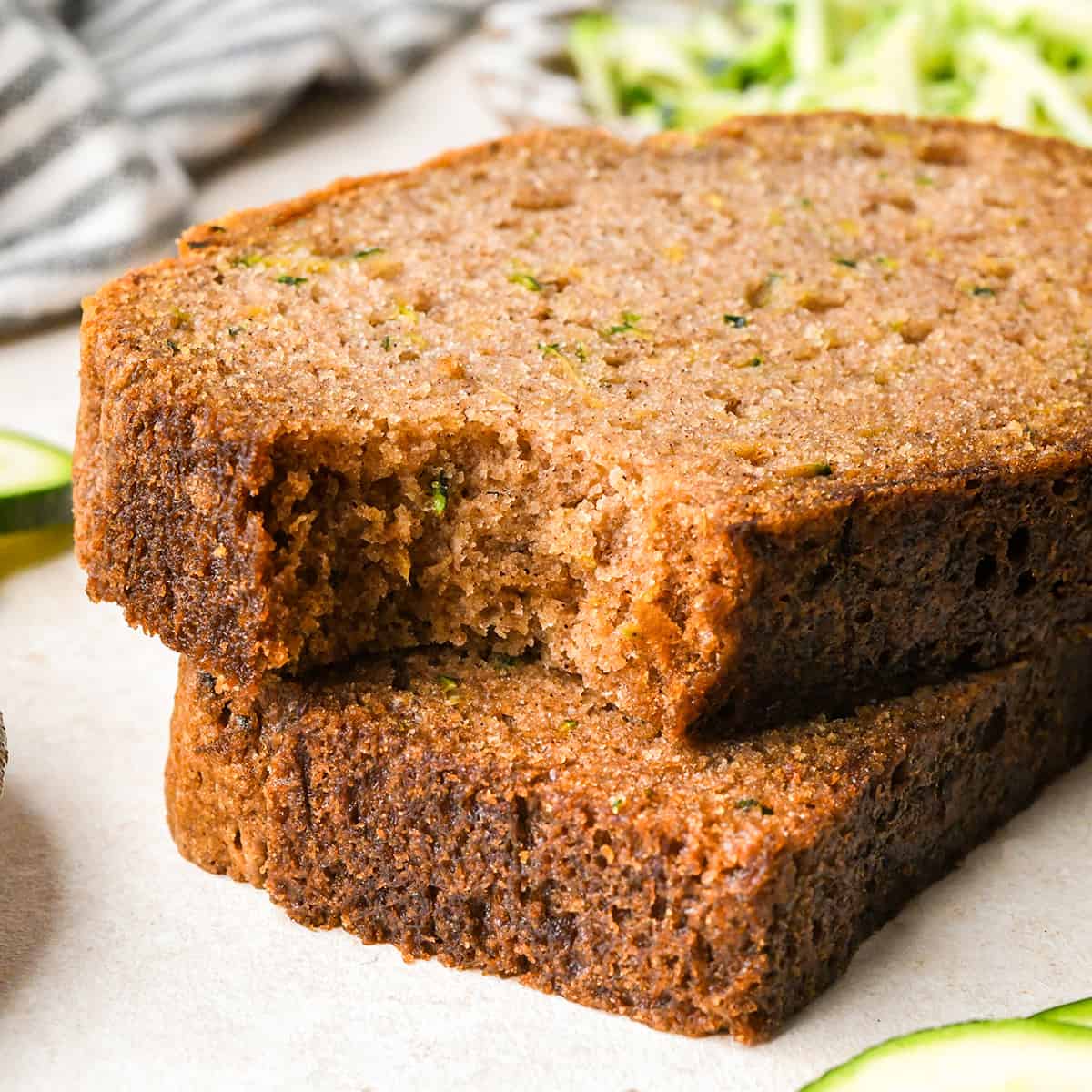 a stack of 2 slices of zucchini bread, the top one with a bite taken out of it