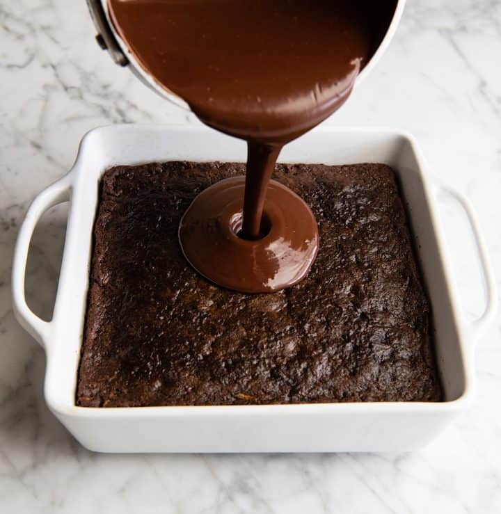 front view of chocolate ganache being poured onto the baked chocolate zucchini cake