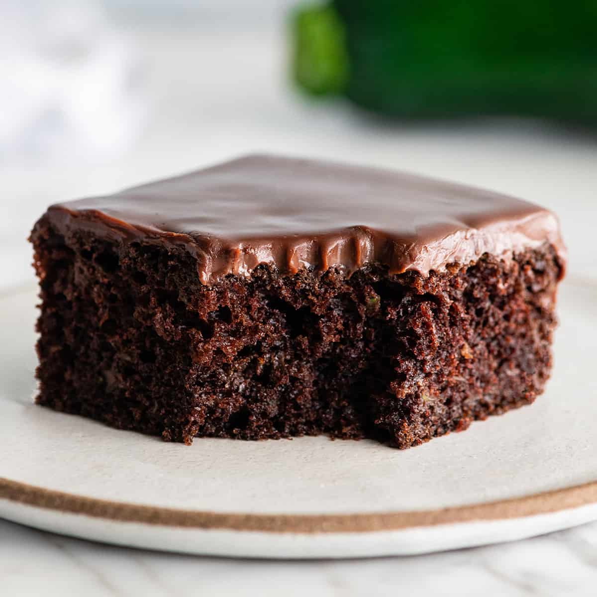 front view of a slice of chocolate zucchini cake with a bite taken out of it