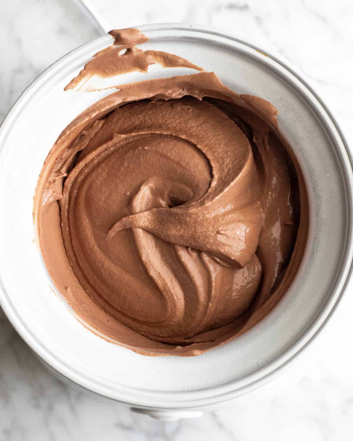 how to make chocolate ice cream - churned chocolate ice cream in the container of an ice cream maker. The thick and creamy, smooth texture is visible.