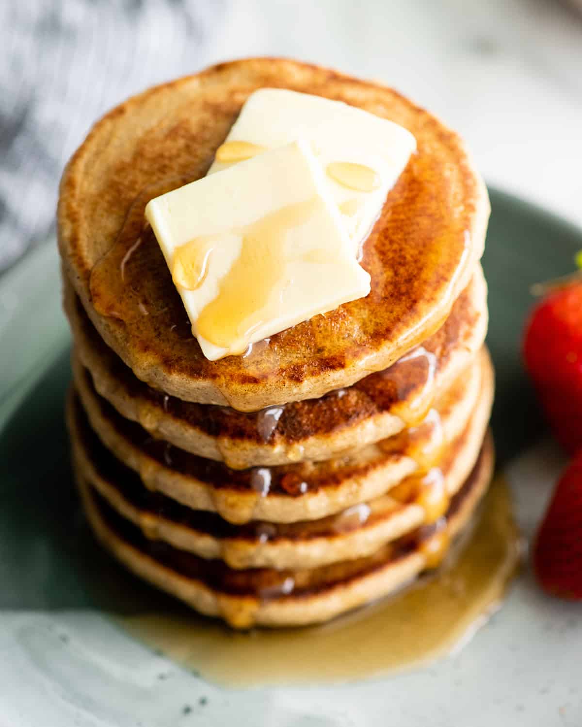 overhead view of a stack of 5 banana oat pancakes with butter and syrup