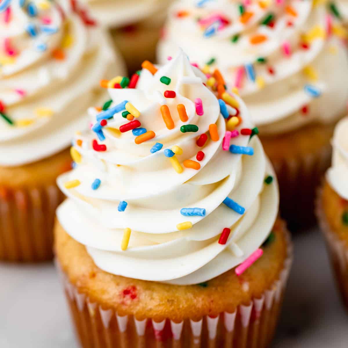 vanilla frosting piped on top of a vanilla cupcake topped with sprinkles