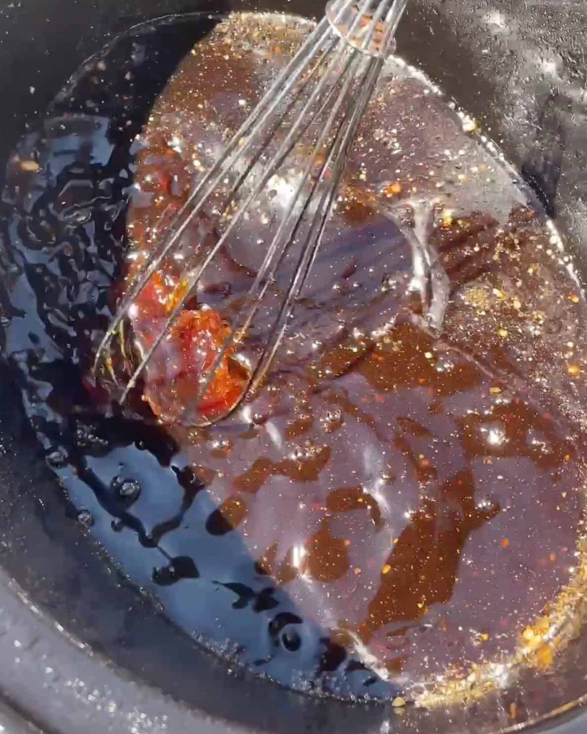 making slow cooker teriyaki chicken - whisking the sauce in a container of a crock pot wiht a metal whisk