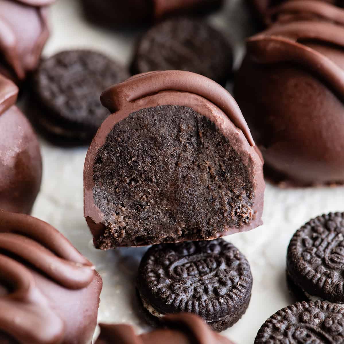 These Oreo Ballsย are an easy and delicious no-bake dessert made with only 4 ingredients! They are so good you won't be able to eat just one. Watch the video and follow the step-by-step photo instructions to learn how to make the best Oreo truffles recipe ever! A perfect summer treat and sure to be the star of your Christmas dessert platter.ย front view of an Oreo ball cut in half so the inside of is visible