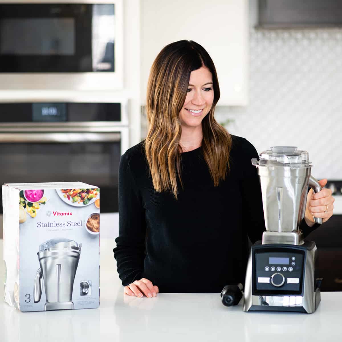 front view of woman holding Vitamix stainless steel container