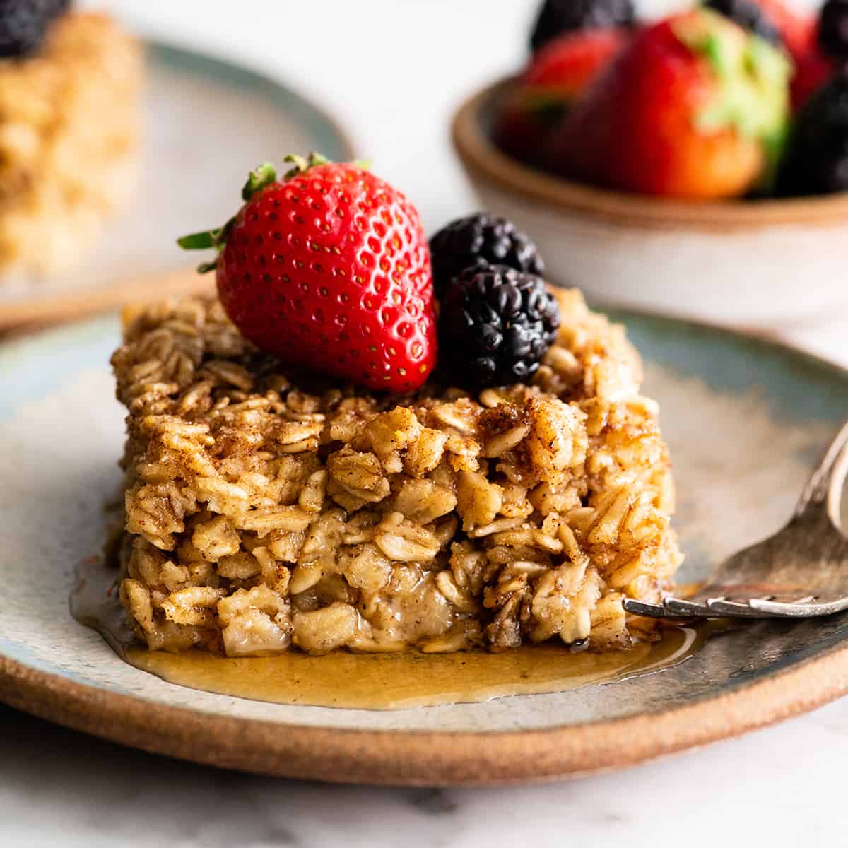 a piece of baked oatmeal on a plate with syrup and berries