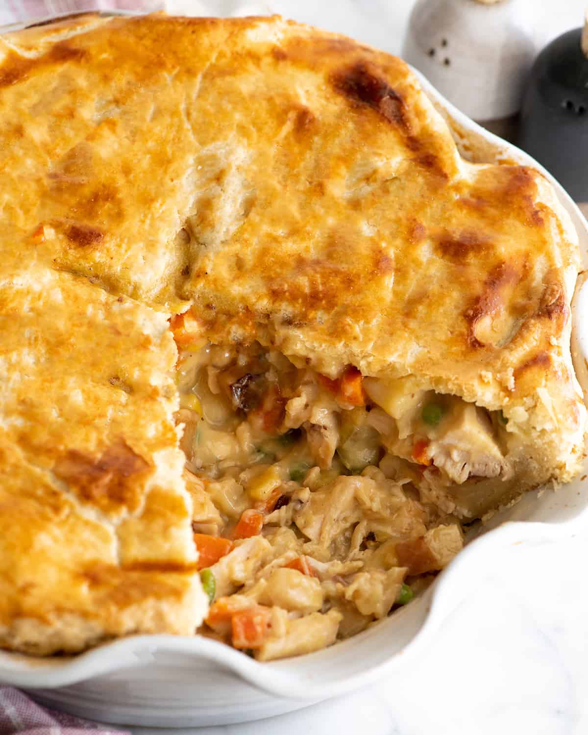 chicken pot pie in a pie dish with one piece cut out