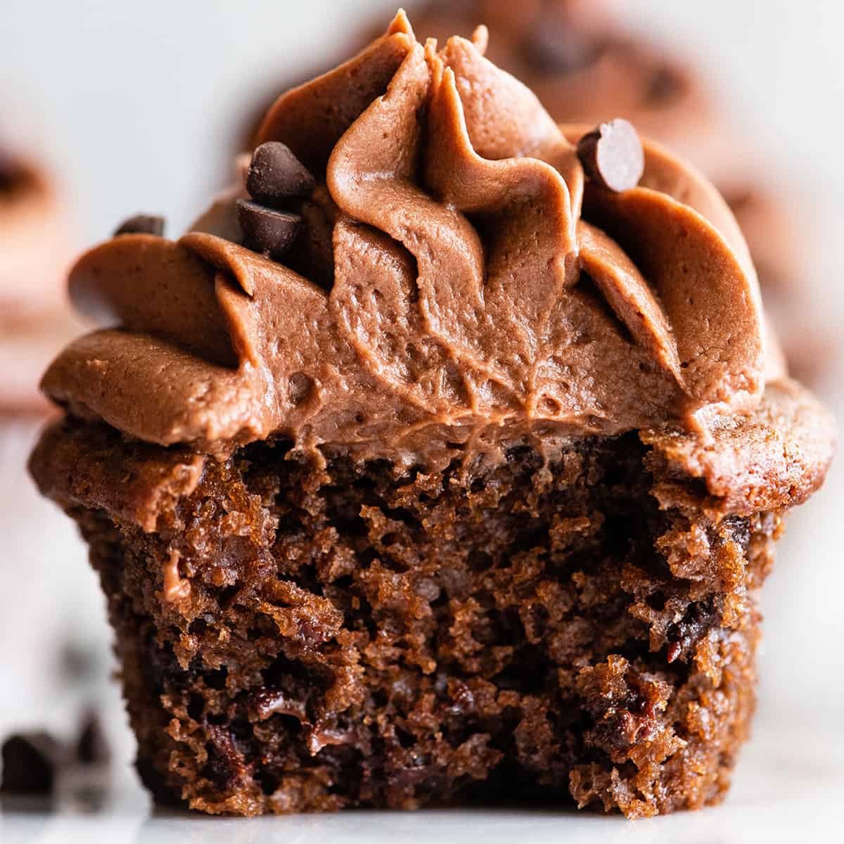 up close photo of chocolate frosting on top of a chocolate cupcake with a bite taken out of it