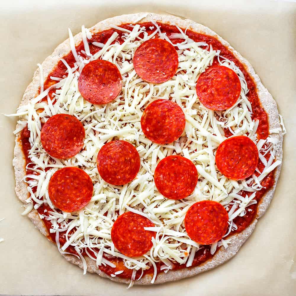 overhead photo showing whole wheat pizza crust with toppings before baking