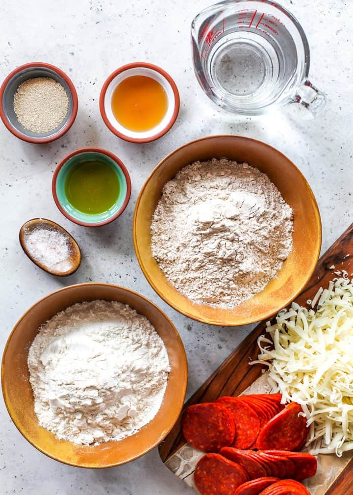 This whole wheat pizza dough recipe is healthy, easy, delicious and made with only 7 ingredients! Whole wheat pizza crust is crispy on the outside and chewy on the inside, making it the perfect healthy alternative for pizza nights! overhead view of the ingredients in this whole wheat pizza dough recipe