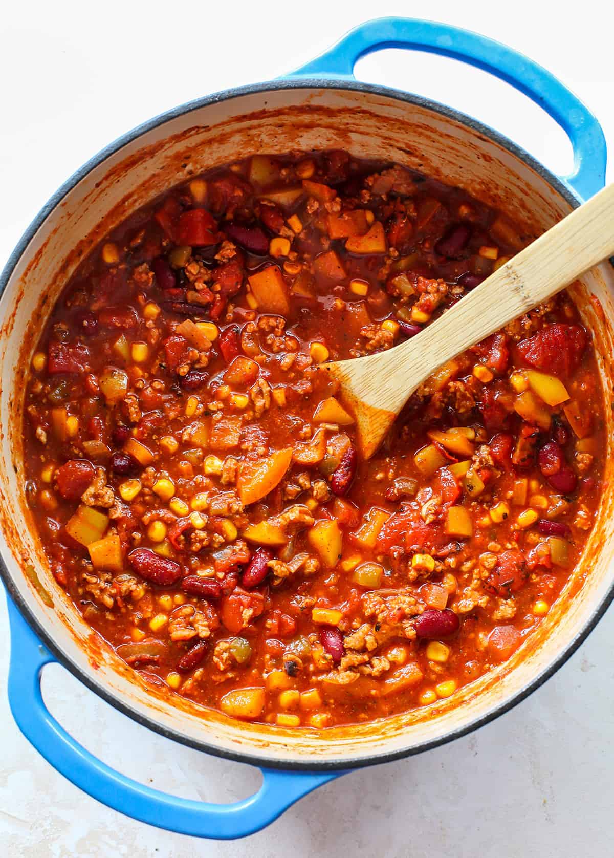 overhead photo of a pot of turkey chili with a spoon