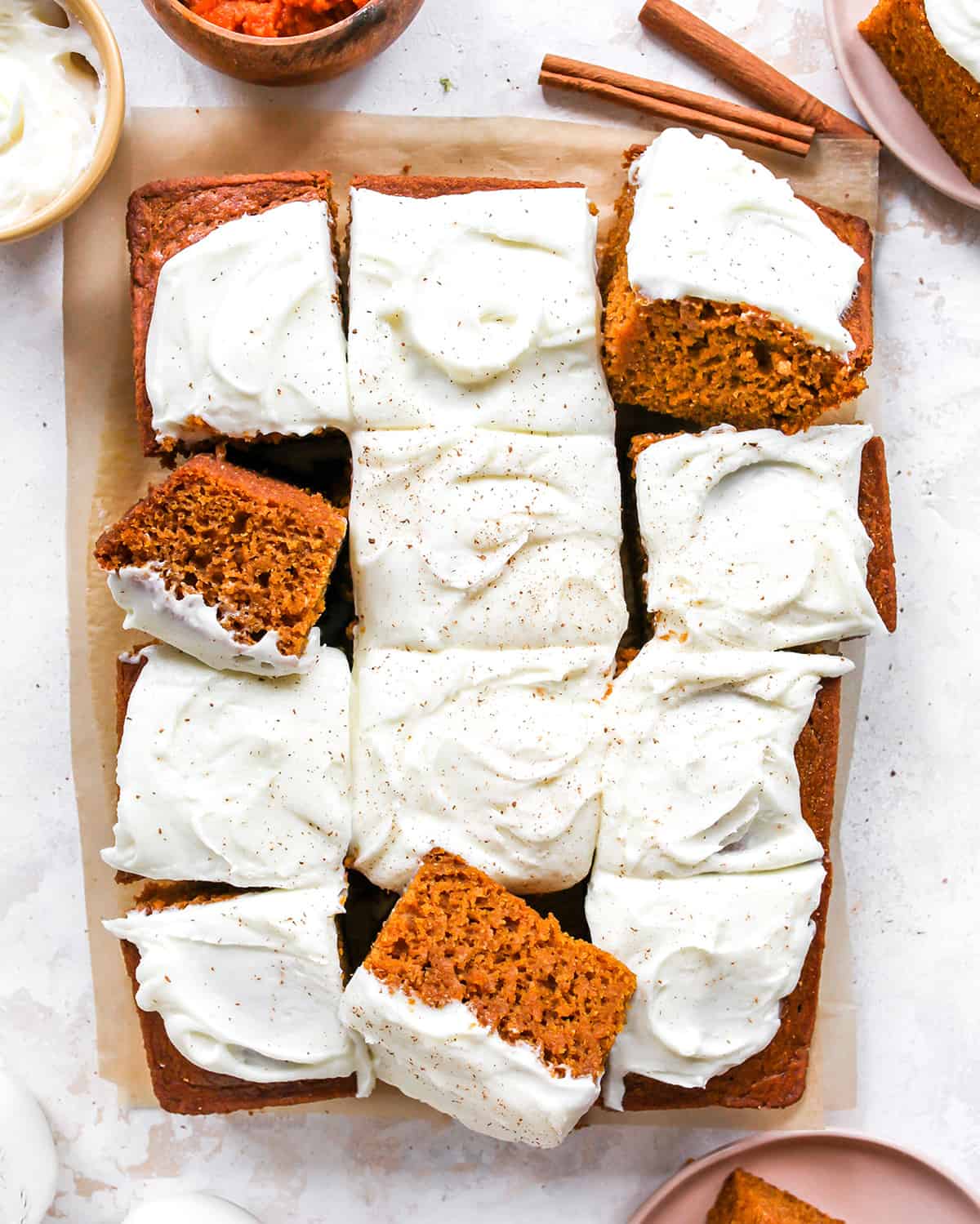 Overhead view of a Pumpkin Cake with cream cheese frosting cut into 12 pieces