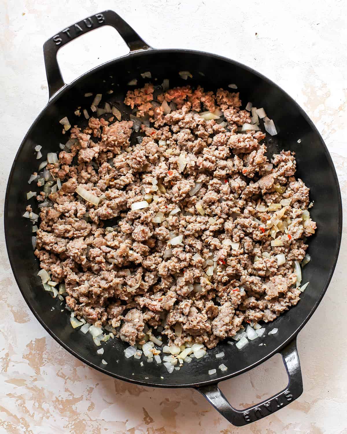making sausage cream cheese dip - raw breakfast sausage, minced garlic and diced onion in a black cast iron skillet after cooking