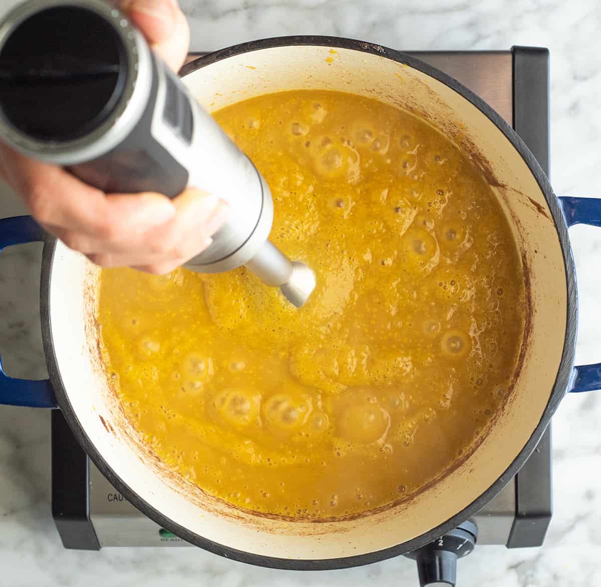 blending butternut squash soup with an immersion blender