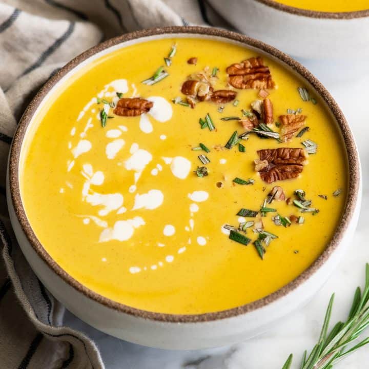 front view of a bowl of butternut squash soup with cream, herbs and nuts 