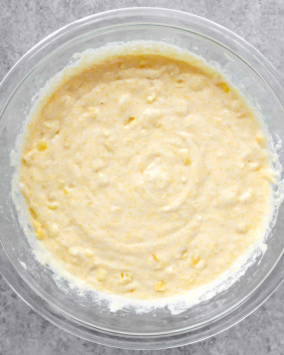 photo showing how to make cornbread - final cornbread batter in a glass bowl on a gray surface