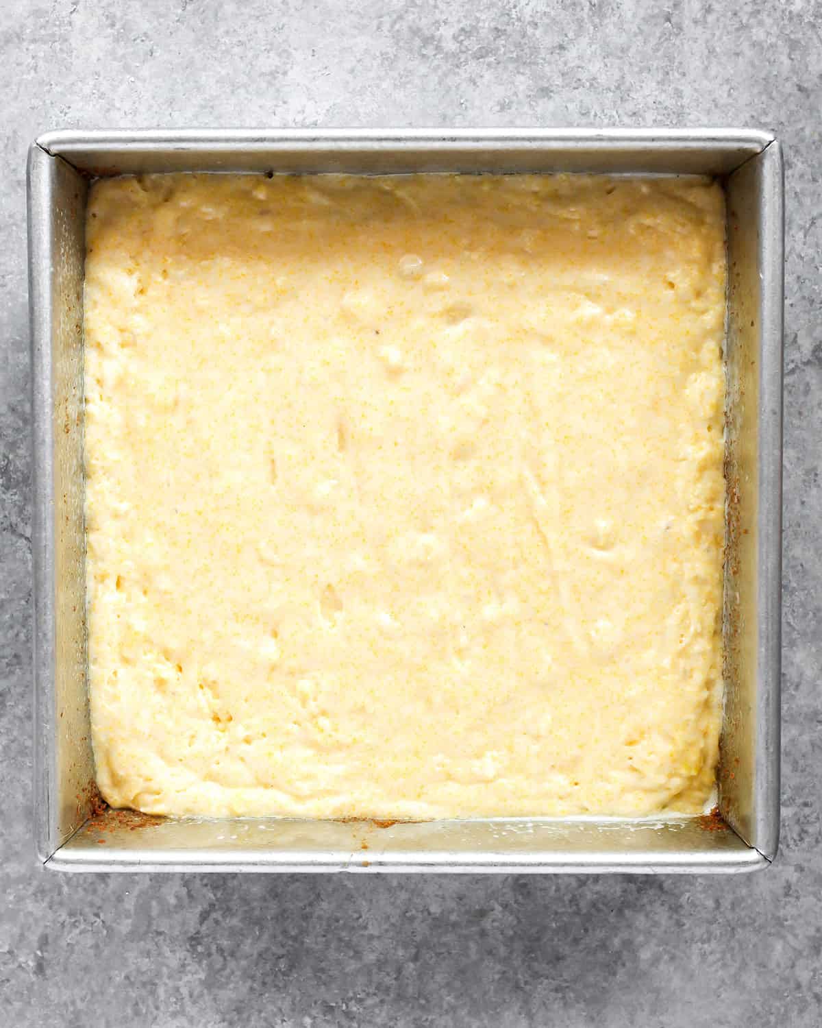 photo showing how to make cornbread - cornbread batter spread evenly into a metal, square baking dish before baking