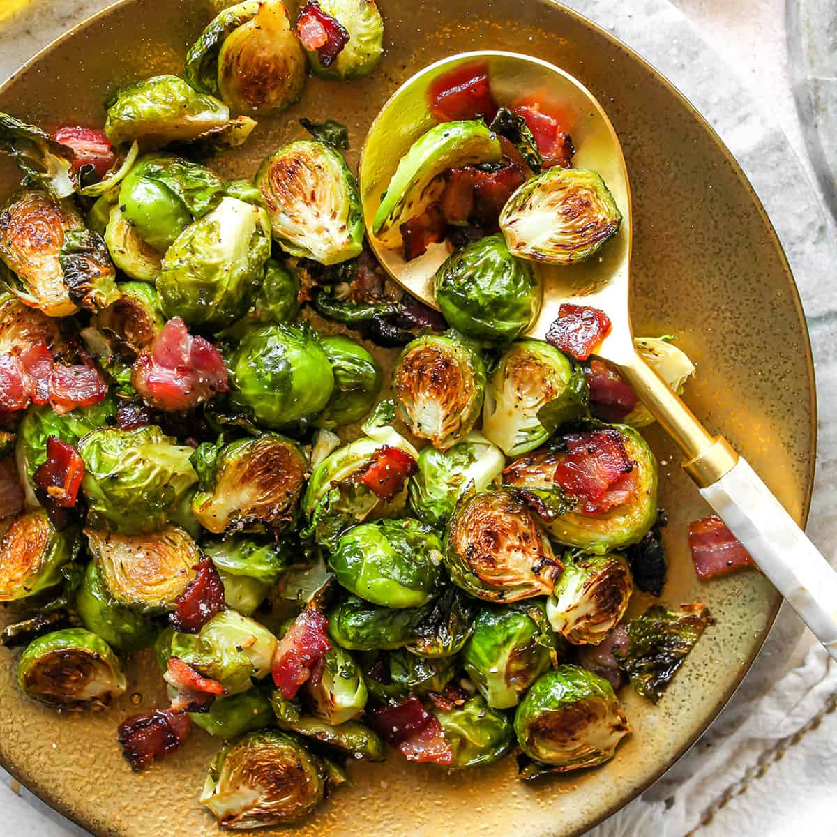 overhead view of Roasted Brussel Sprouts with Bacon on a plate with a serving spoon