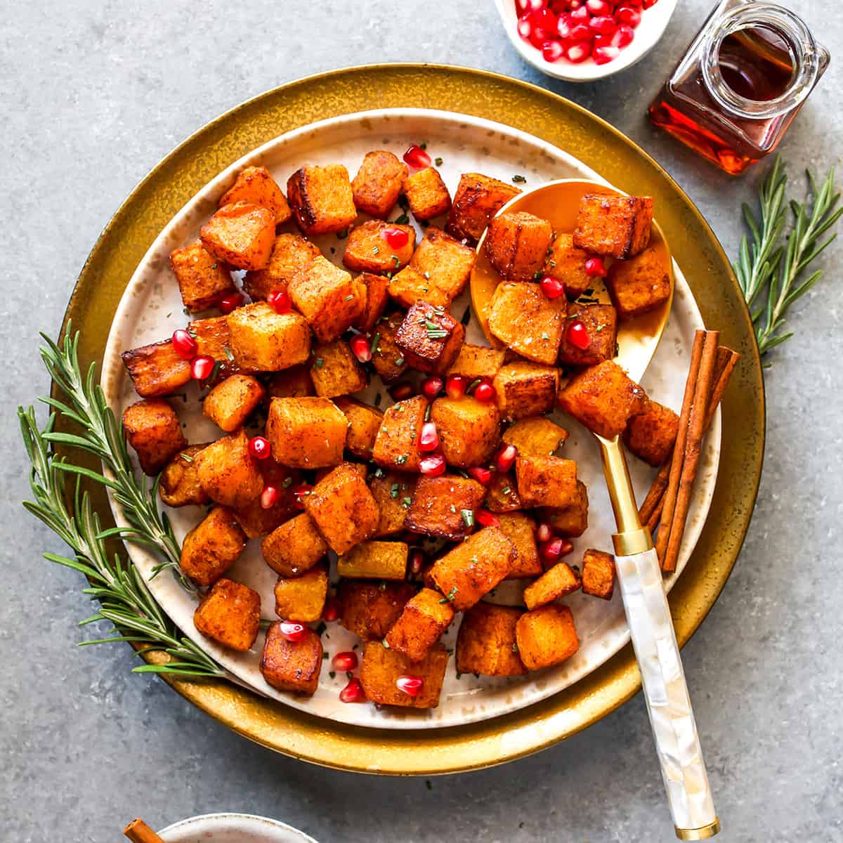 overhead view of a plate of Cinnamon Roasted Butternut Squash with pomegranates and rosemary