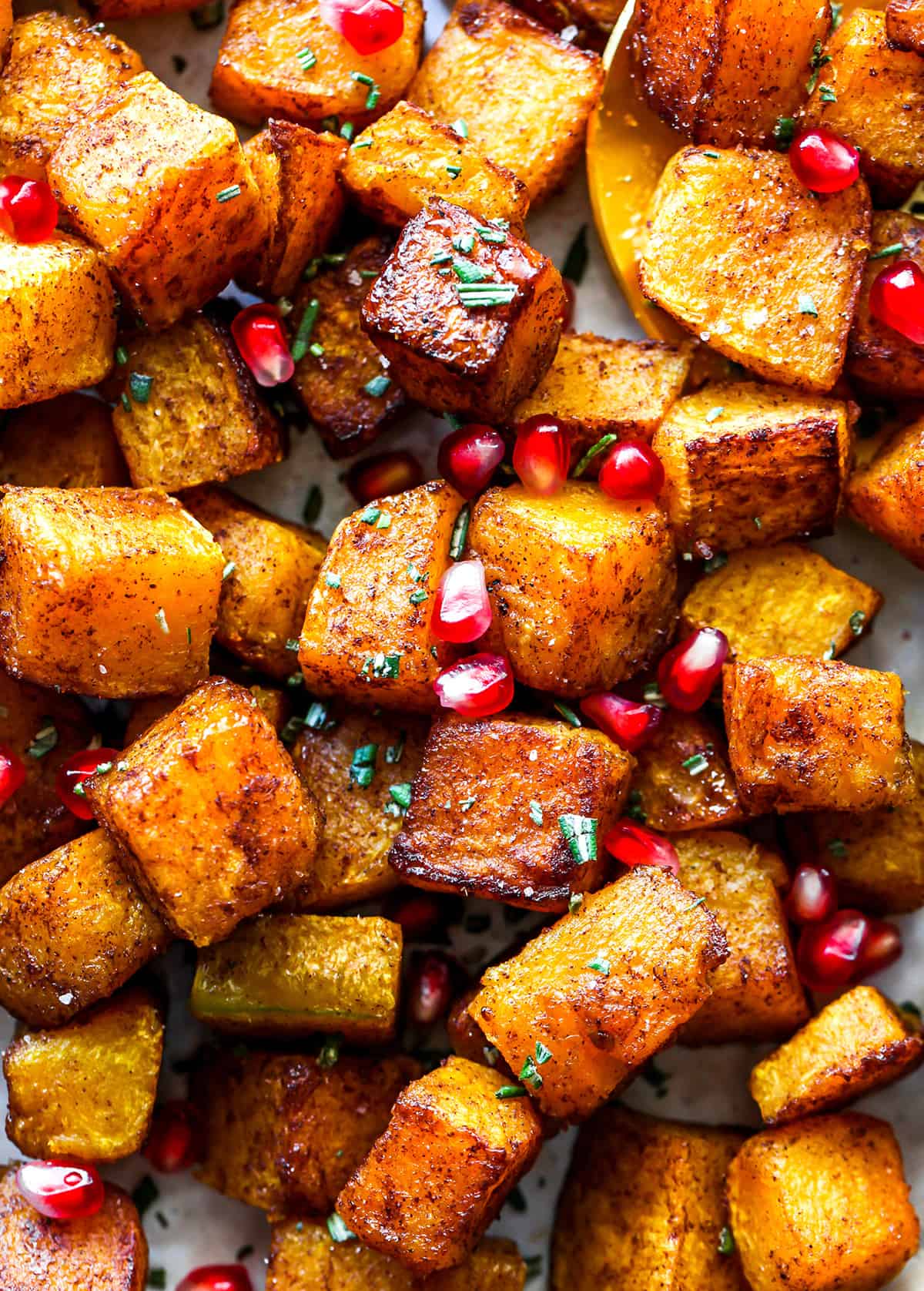 up close photo of Cinnamon Roasted Butternut Squash Recipe with pomegranates and rosemary