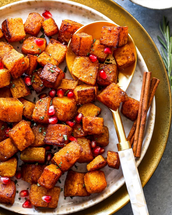 Cinnamon Roasted Butternut Squash on a plate with a spoon and pomegranate seeds