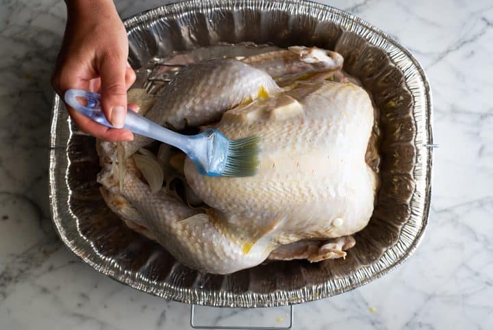 This Roast Turkey Recipe is the absolute best. A flavorful turkey brine, robust aromatics and many tips and tricks results in the most delicious Thanksgiving turkey ever. Learn how easy cooking a turkey can be with our step-by-step photos and video. overhead photo showing how to cook a turkey