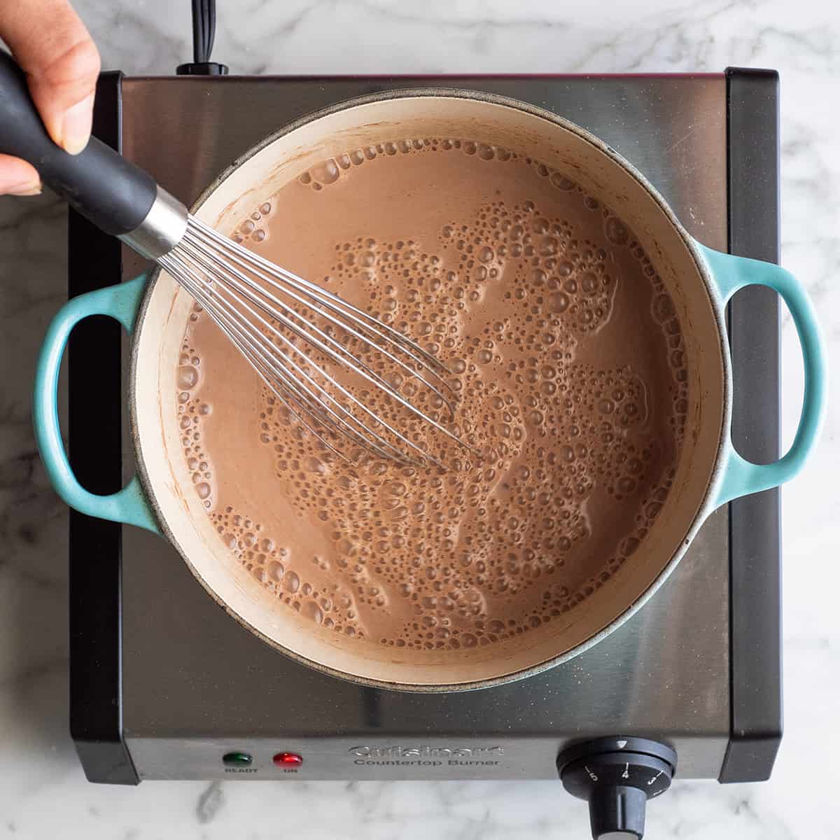 How to Make Hot Chocolate whisking ingredients together in a dutch oven