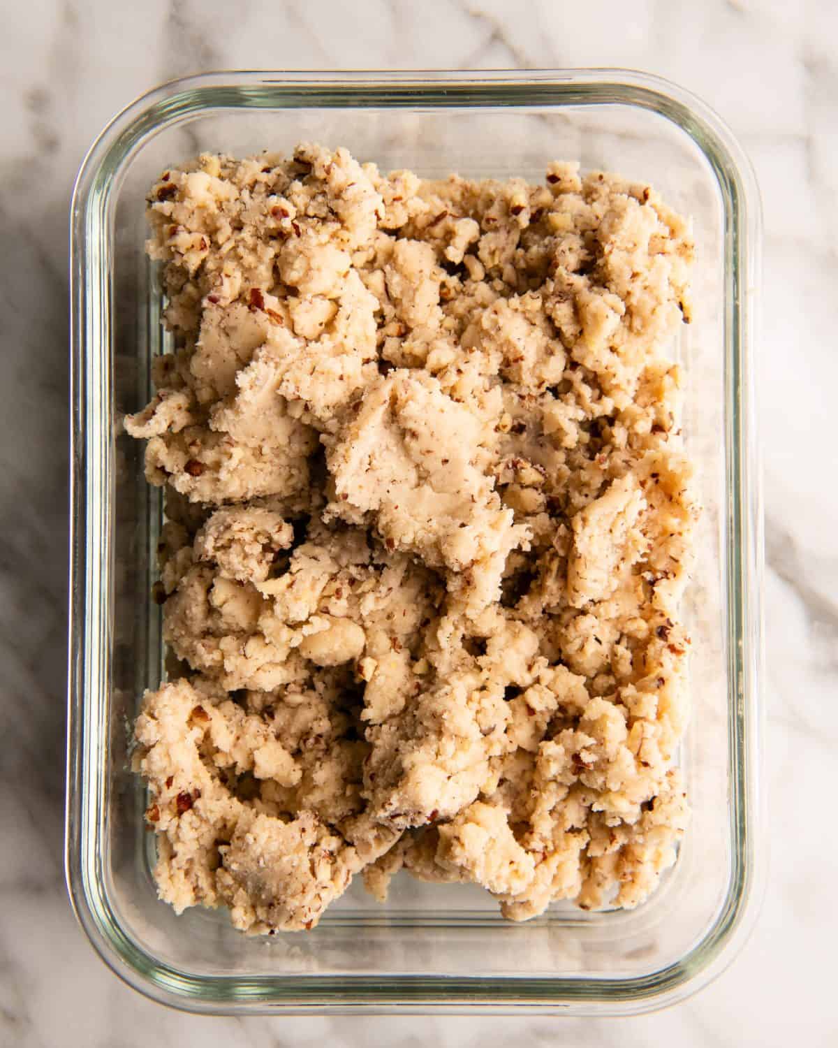 the dough for this pecan snowball cookies recipe in a rectangular glass container on a marble surface to be chilled