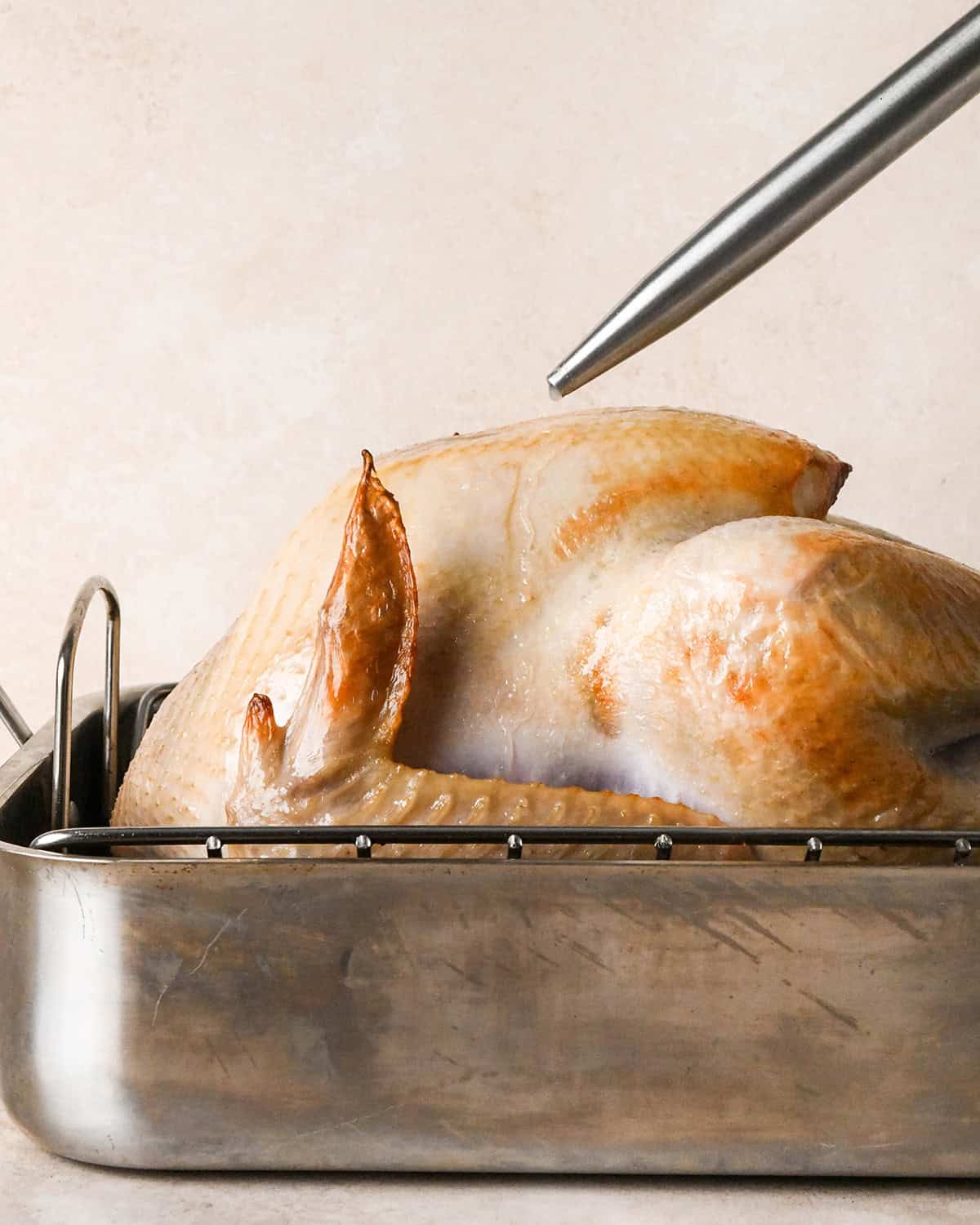 oven roasted turkey being basted in a roasting pan after roasting for 30 minutes in the oven