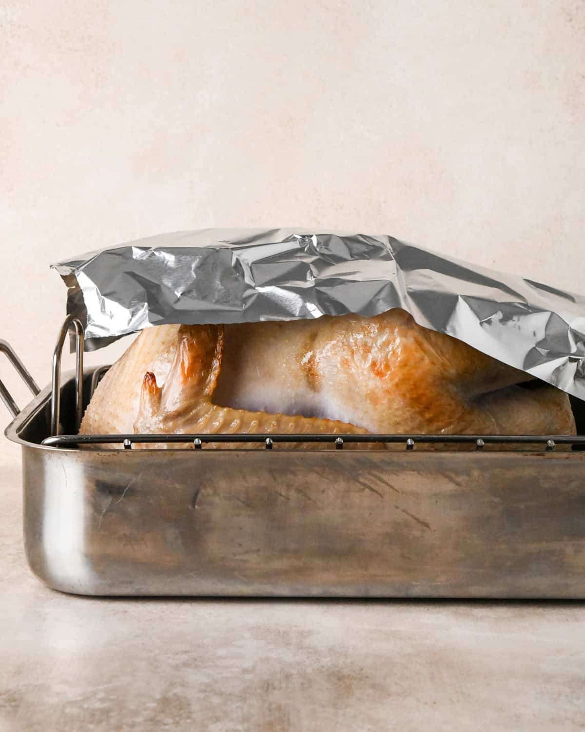 oven roasted turkey covered with foil in a roasting pan after roasting for 30 minutes in the oven