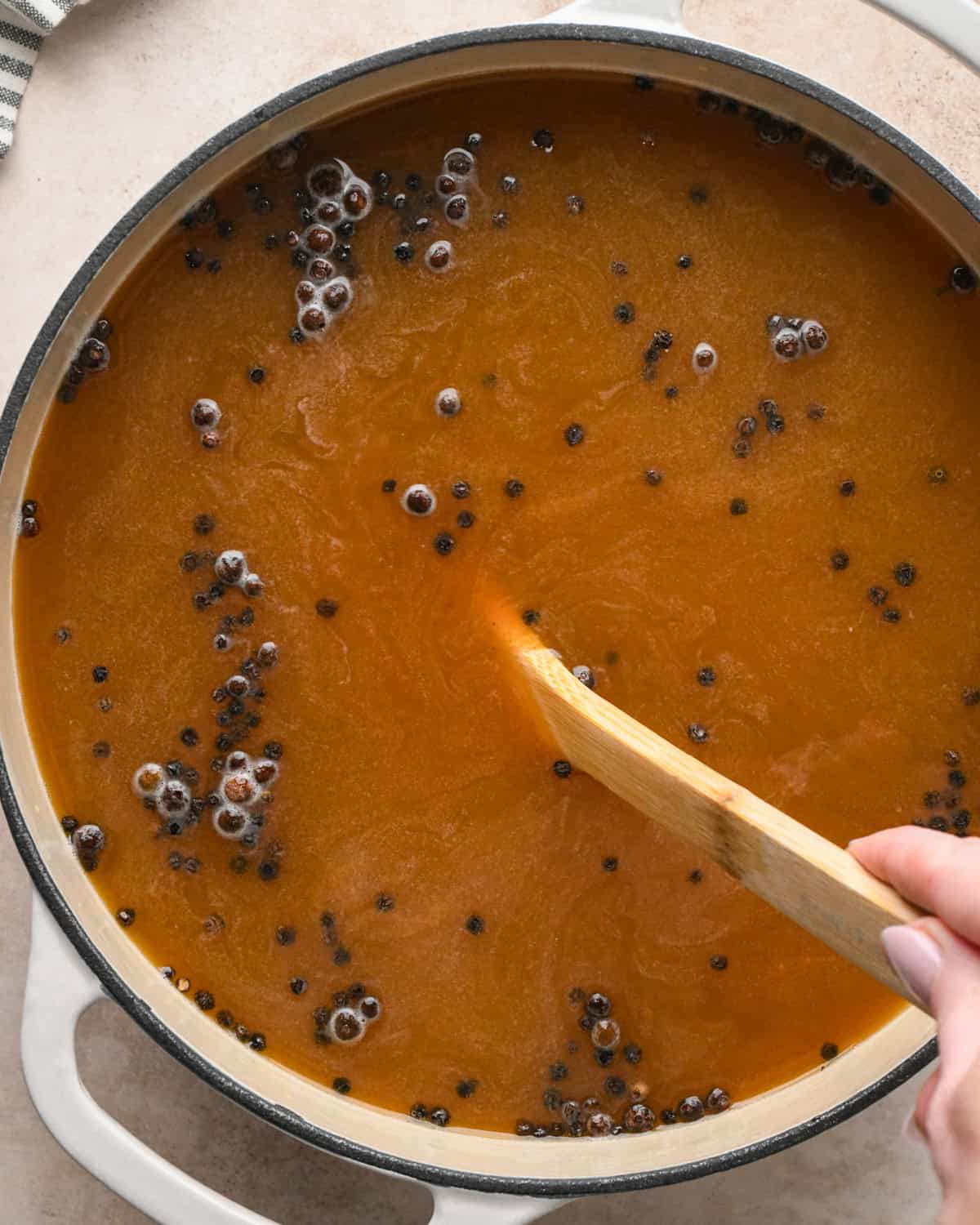 turkey brine being cooked in a pot and stirred with a wooden spoon to make this roast turkey recipe