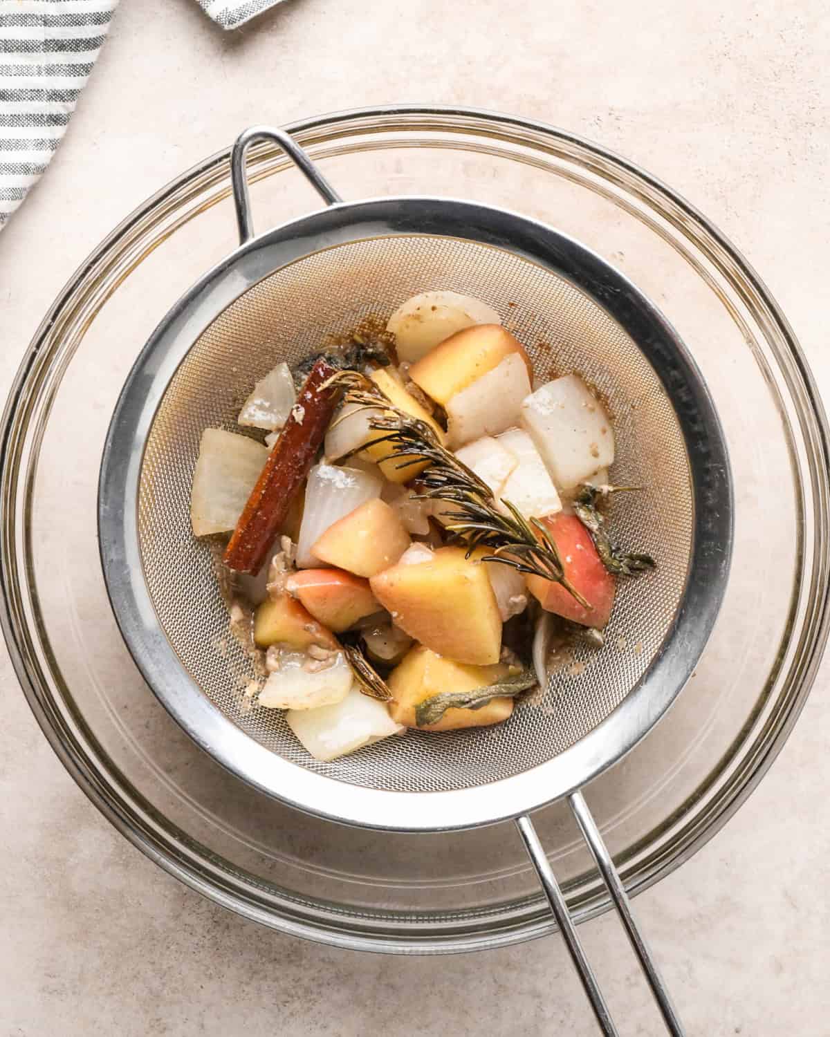 the aromatics from the roast turkey being strained through a metal strainer into a bowl