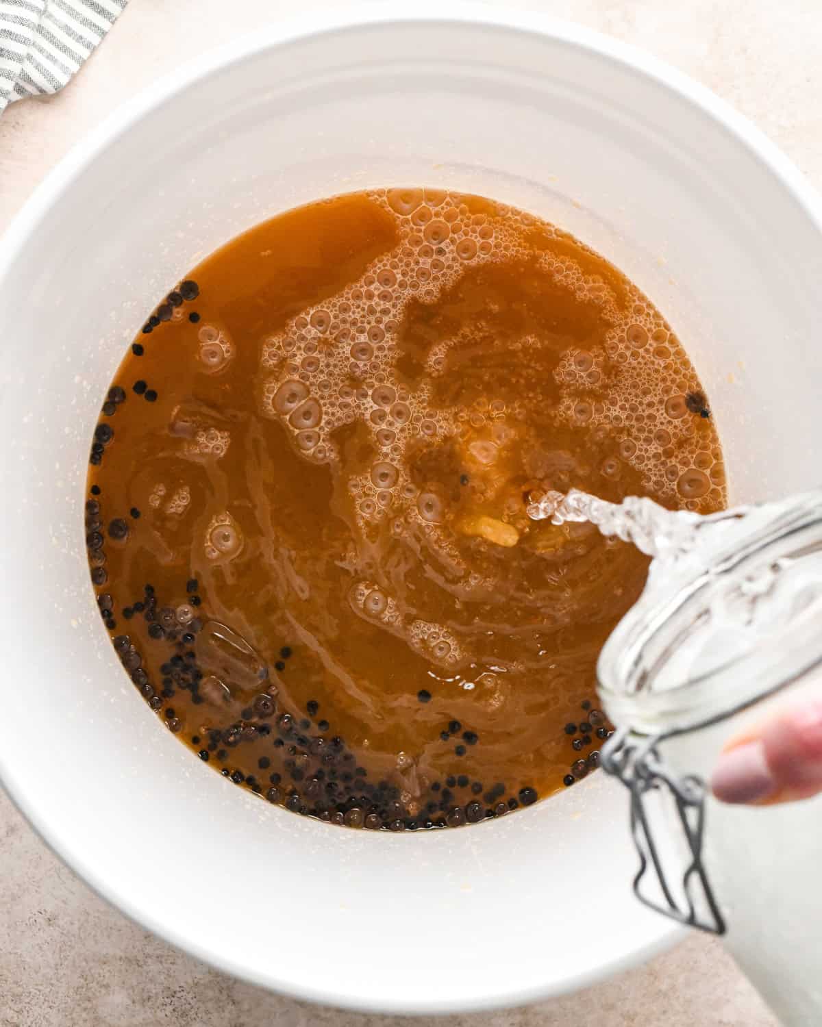 ice water being poured into turkey brine in a white bucket to make oven roasted turkey