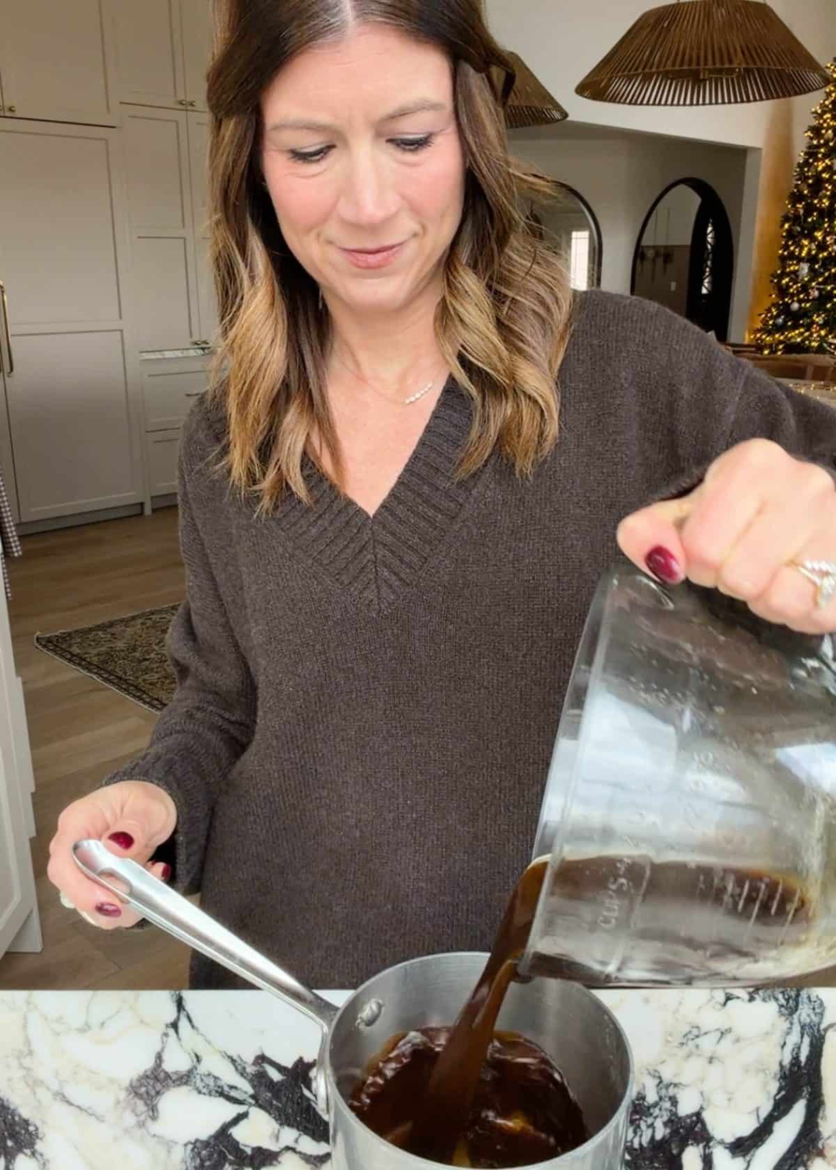 making slow cooker pot roast recipe - Laura from joyfoodsunshine pouring the sauce from the glass batter bowl into a saucepan to cook and thicken it