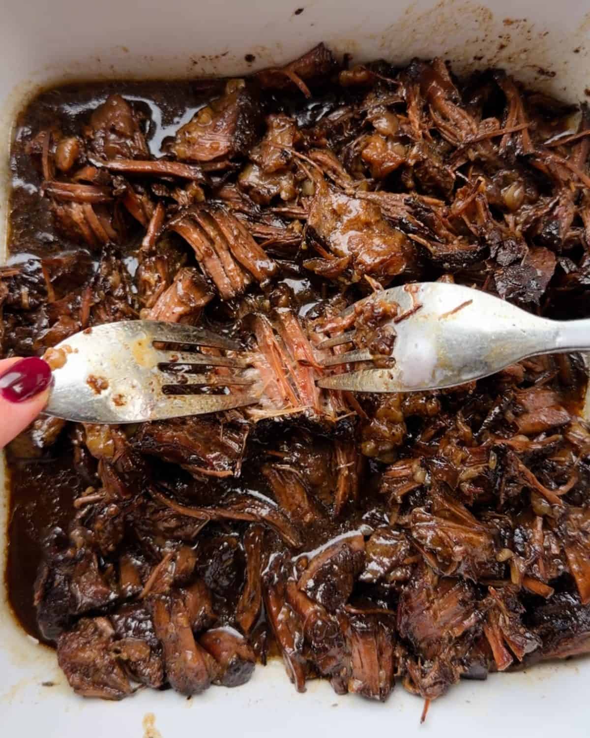 making slow cooker pot roast recipe - two forks shredding the crock pot roast recipe